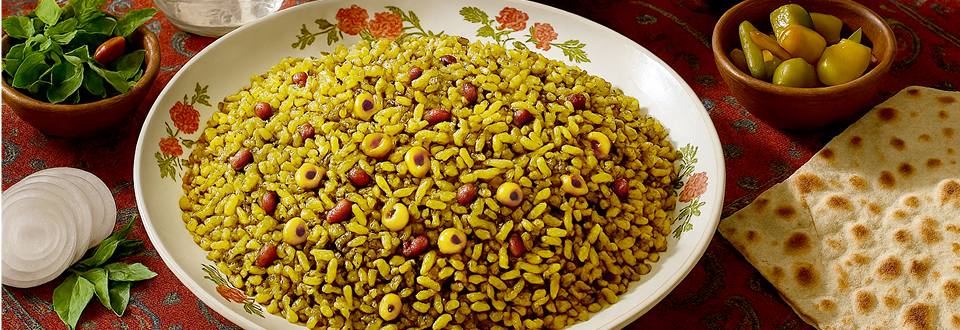 Plat de loobia polo shirazi : riz persan safrané mélangé à des haricots verts et de la viande, servi chaud dans une assiette, montrant une texture de riz pilaf aux couleurs chaudes avec des morceaux de légumes et de viande.